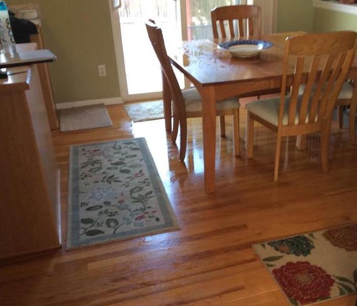 Kitchen table has water underneath it on the wood floor. 