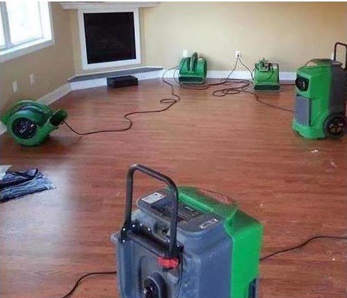 Restoration machines are cleaning water damage in a home.